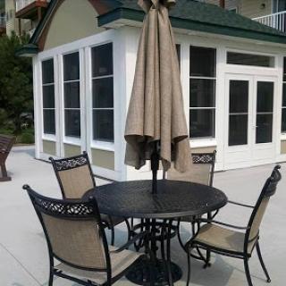 A cozy outdoor seating area featuring a table, four chairs, and an umbrella.
