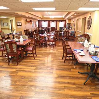 An empty dining room with neatly arranged tables and chairs on a hardwood floor.