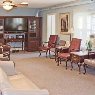 A well-furnished living room with a seating area, television, and carpeted floor.