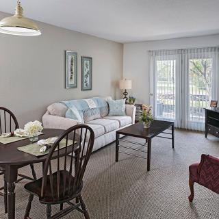 A cozy living room with a sofa, dining area, and ample natural light.