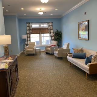 A cozy living room with a sofa, chairs, and a lamp against blue walls.