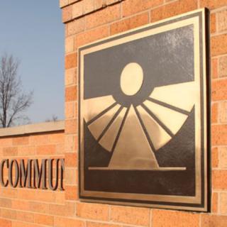 A bronze plaque with a stylized sun design mounted on a brick wall.