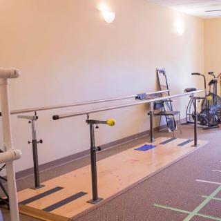 A rehabilitation studio featuring a ballet barre and various exercise equipment.