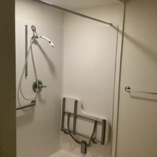 An accessible shower with handrails and a foldable seat.