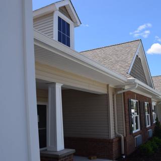 A residential house with a pitched roof and porch under a clear blue sky.