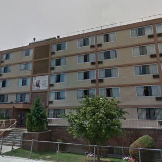 A multi-story apartment building with neatly maintained landscaping.