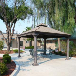 An outdoor patio area with a gazebo and furniture surrounded by trees.