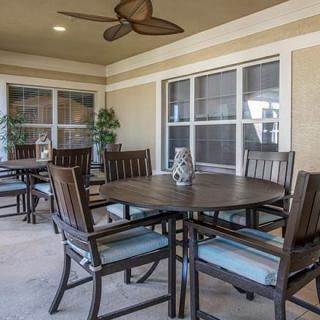 An outdoor patio area with tables and chairs under a ceiling fan.