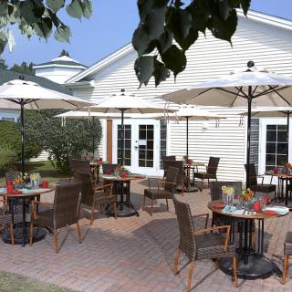 A sunny outdoor patio with tables, chairs, and umbrellas at a caf or restaurant.