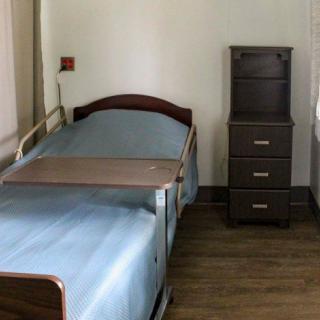 An empty hospital room with a single bed and bedside table.