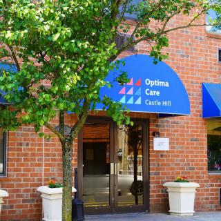 Entrance of a brick building with a blue awning and surrounding greenery.
