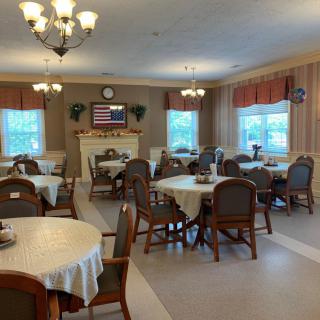 A cozy dining area with multiple tables and chairs, decorated with chandeliers and a fireplace.