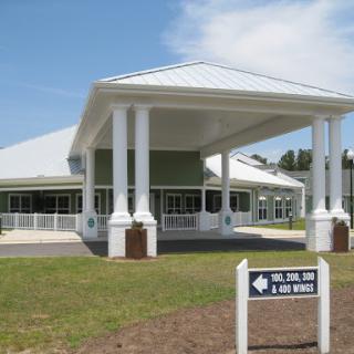A modern commercial building featuring a large entrance with columns and a sign directing visitors.