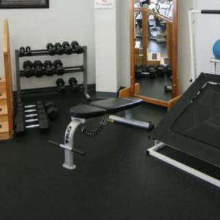 A gym with various fitness equipment including dumbbells and a bench.