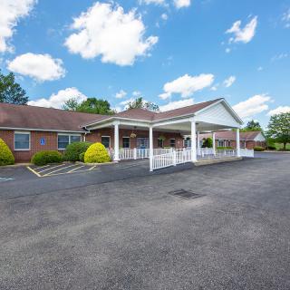 A single-story building with a spacious parking lot under a partly cloudy sky.
