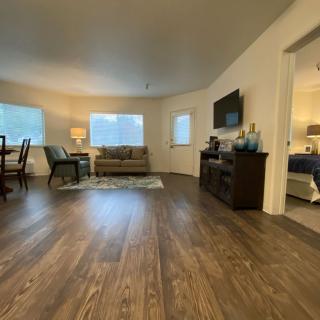A spacious living room with a hardwood floor, modern furniture, and a dining area.