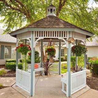 A charming gazebo surrounded by greenery with hanging baskets in a garden setting.