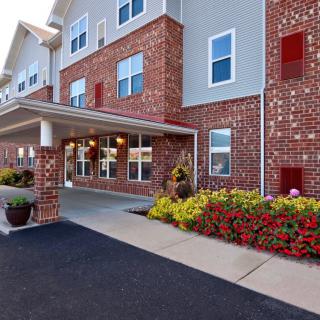 A brick building with a covered entrance and colorful flower beds.