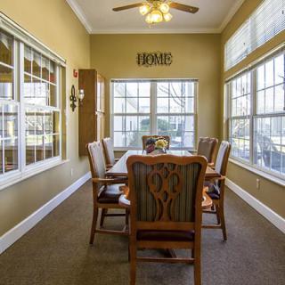 A cozy dining room with large windows and a ceiling fan.