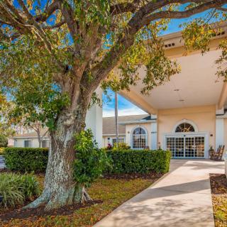 A building entrance with a large tree and landscaped walkway.