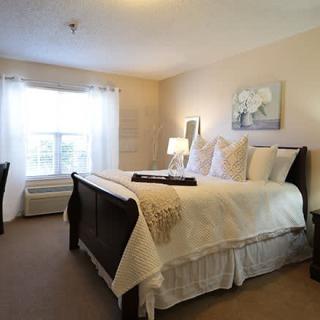 A cozy and well-decorated bedroom with a large bed, bedside lamps, and a window letting in natural light.