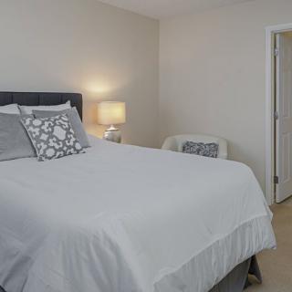 A cozy bedroom with a neatly made bed, decorative pillows, and a lamp on the nightstand.