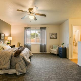 A cozy bedroom with a large bed, ceiling fan, and stylish decor.
