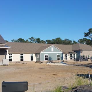 A newly constructed residential building surrounded by an unfinished landscape under a clear blue sky.