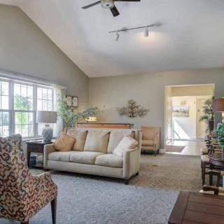 A cozy living room with a sofa, patterned chair, and large windows letting in natural light.