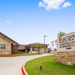 A view of an assisted living and memory care facility with its sign displayed at the entrance.