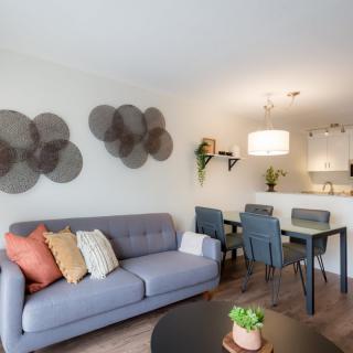 A modern living room with a cozy sofa, dining area, and stylish wall art.