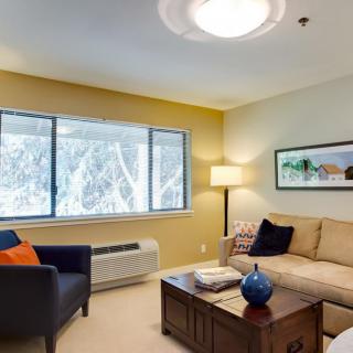 A cozy living room with a sofa, coffee table, and large window.