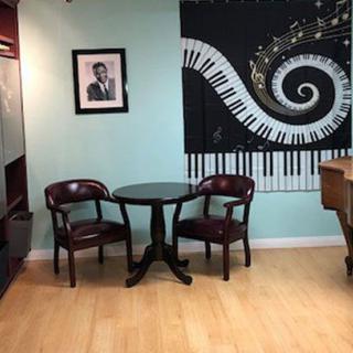 A small seating area with two chairs and a round table, set against a wall featuring a piano-themed mural.