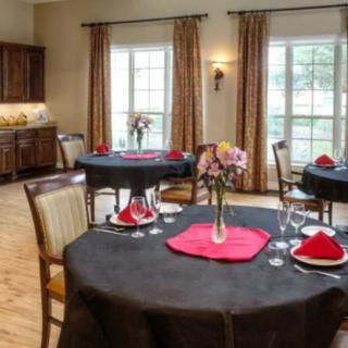 A well-appointed dining room with elegantly set tables, featuring red napkins and floral centerpieces.