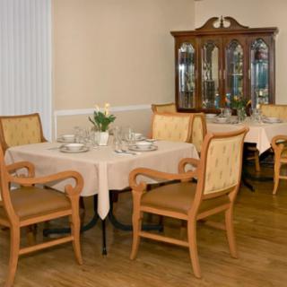 A cozy dining room with a set of wooden chairs and tables, complemented by a china cabinet in the background.