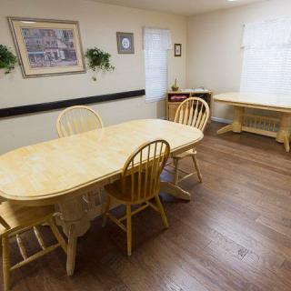 A cozy dining room with wooden tables and chairs, decorated with artwork and plants.