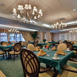 A well-decorated dining room with elegant chandeliers and tables set for a meal.