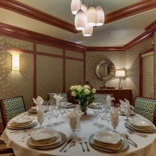 A beautifully set dining table in an elegant room with a chandelier and floral centerpiece.