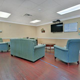 A cozy waiting room with comfortable chairs and a television on the wall.