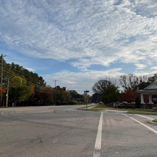 A quiet suburban intersection under a cloudy sky.