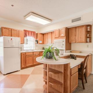 A spacious kitchen with wooden cabinets, an island, and a bright atmosphere.