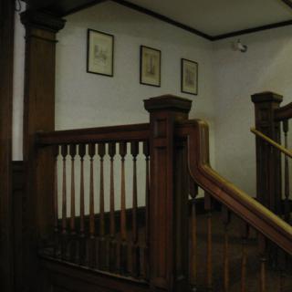 A vintage wooden staircase with framed artwork on the wall.