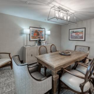 A stylish dining room featuring a wooden table, upholstered chairs, and modern lighting.