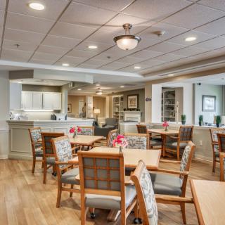 A spacious dining area with neatly arranged tables and chairs, accented with warm lighting and decor.
