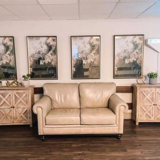 A cozy living room with a cream-colored sofa, surrounded by decorative wooden cabinets and framed artwork on the wall.