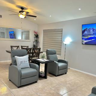 A cozy and modern living room featuring comfortable gray chairs, a dining area, and a television.