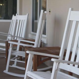 A row of white rocking chairs on a porch, inviting relaxation and conversation.