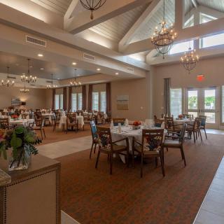 An elegant dining room with chandeliers, natural lighting, and well-arranged tables.