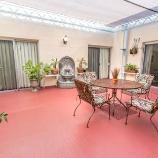 A serene patio setting with decorative plants, a classic fountain, and comfortable seating for relaxation.