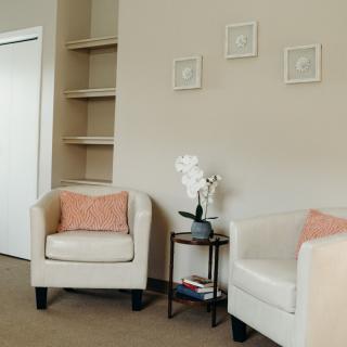 A modern living room with beige chairs and minimalist decor.